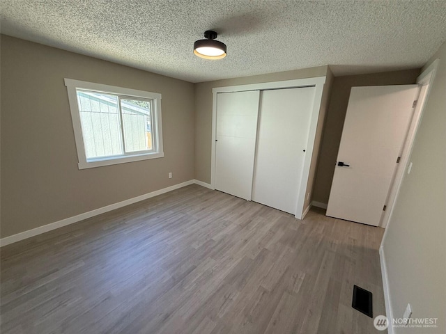 8102 195th St E Unit 95, Spanaway, WA 98387 - unfurnished bedroom with a closet, light wood finished floors, and a textured ceiling