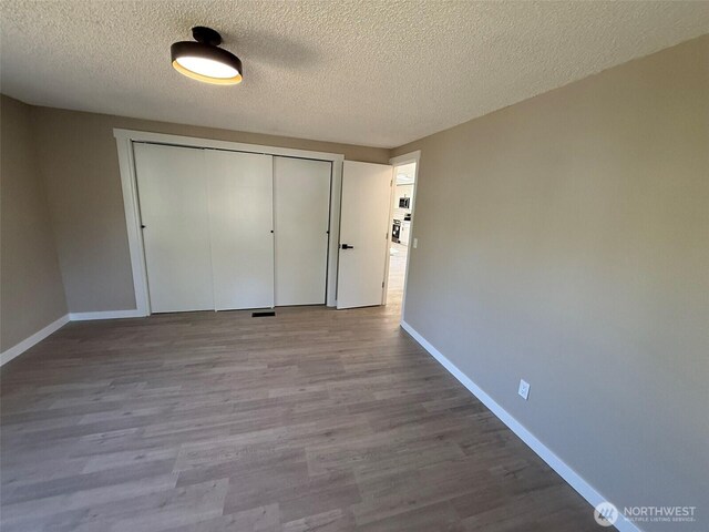 8102 195th St E Unit 95, Spanaway, WA 98387 - unfurnished bedroom with a closet, a textured ceiling, and wood finished floors