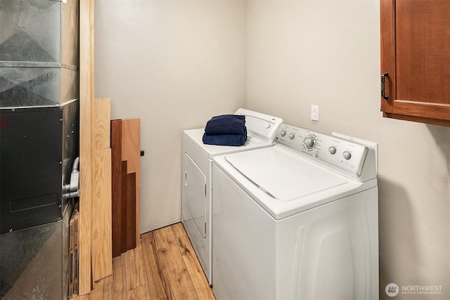 61 Tom And Nita Rd, Cle Elum, WA 98922 - laundry area featuring washing machine and clothes dryer, light wood-style flooring, cabinet space, and heating unit