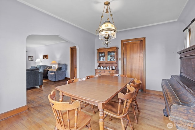 235 S 59th St, Tacoma, WA 98408 - dining space featuring arched walkways, light wood-style flooring, a chandelier, and crown molding
