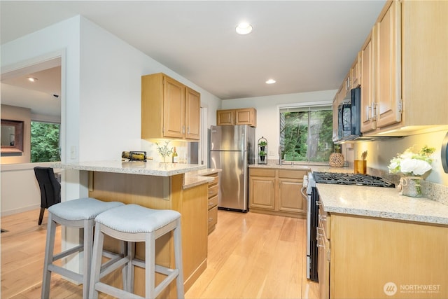 22526 53rd Ave SE, Bothell, WA 98021 - kitchen featuring appliances with stainless steel finishes, a breakfast bar, light wood-type flooring, light brown cabinets, and plenty of natural light