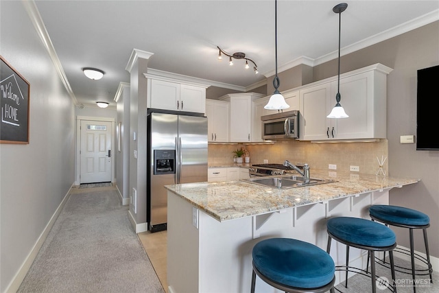 1000 High St Unit 102, Bellingham, WA 98225 - kitchen with stainless steel appliances, a peninsula, white cabinetry, backsplash, and ornamental molding
