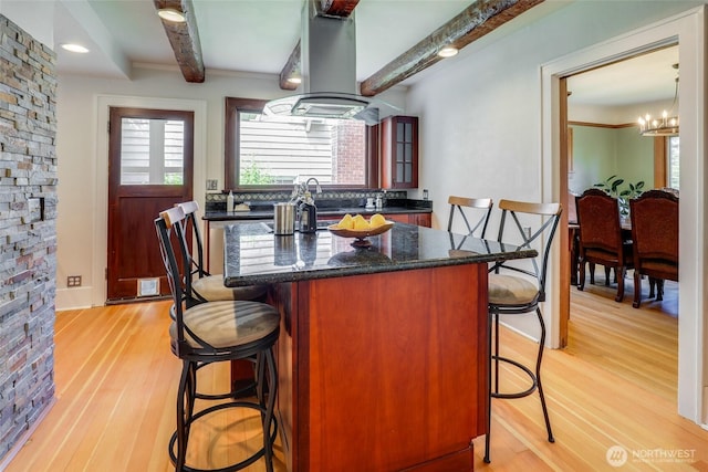 2463 26th Ave E, Seattle, WA 98112 - kitchen featuring island exhaust hood, a kitchen bar, beamed ceiling, light wood-type flooring, and plenty of natural light