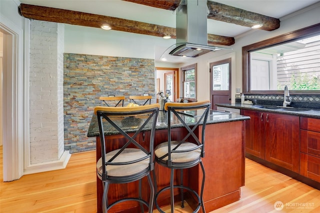 2463 26th Ave E, Seattle, WA 98112 - kitchen with island range hood, light wood-style flooring, a center island, a breakfast bar area, and beam ceiling