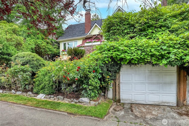 2463 26th Ave E, Seattle, WA 98112 - view of property hidden behind natural elements featuring a chimney, a garage, concrete driveway, and brick siding
