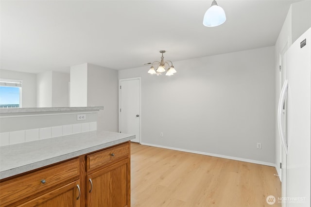 12904 159th St E, Puyallup, WA 98374 - kitchen featuring light wood finished floors, freestanding refrigerator, a chandelier, brown cabinetry, and light countertops