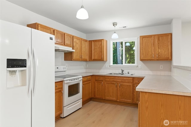 12904 159th St E, Puyallup, WA 98374 - kitchen with white appliances, under cabinet range hood, light wood-style flooring, decorative light fixtures, and brown cabinetry