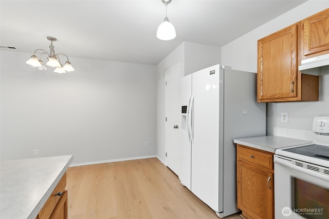 12904 159th St E, Puyallup, WA 98374 - kitchen with white appliances, light wood-style flooring, a chandelier, brown cabinetry, and hanging light fixtures