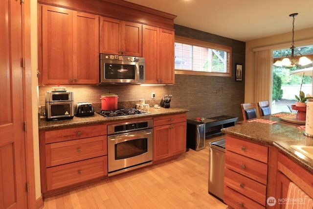 4442 Prestwick Ln SE, Lacey, WA 98513 - kitchen featuring appliances with stainless steel finishes, brown cabinets, decorative backsplash, and light wood-type flooring