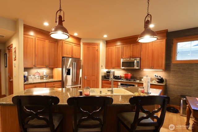 4442 Prestwick Ln SE, Lacey, WA 98513 - kitchen featuring stainless steel appliances, hanging light fixtures, tasteful backsplash, an island with sink, and stone counters