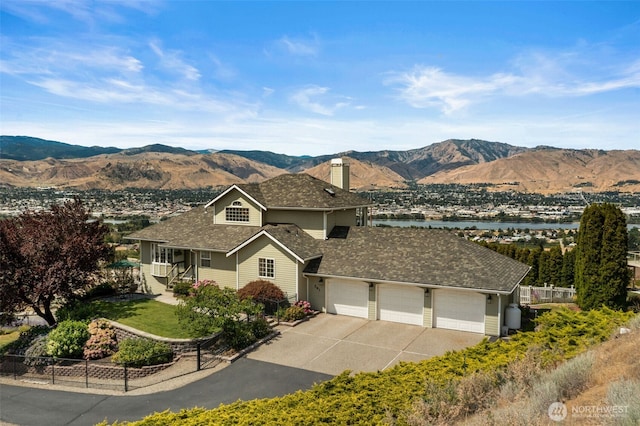 591 Daniels Dr NE, East Wenatchee, WA 98802 - view of front facade featuring driveway, a garage, a chimney, and a water and mountain view
