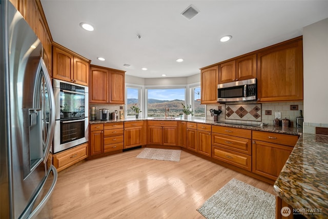 591 Daniels Dr NE, East Wenatchee, WA 98802 - kitchen with appliances with stainless steel finishes, brown cabinets, tasteful backsplash, and recessed lighting