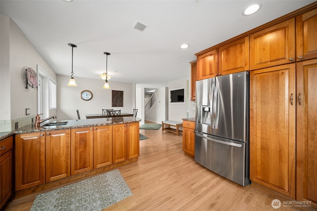 591 Daniels Dr NE, East Wenatchee, WA 98802 - kitchen with stainless steel fridge, brown cabinets, dark stone counters, light wood-style floors, and a peninsula