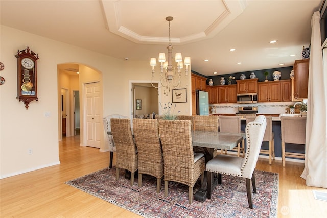 120 Cascadia Loop, Sequim, WA 98382 - dining room with arched walkways, light wood-style flooring, a raised ceiling, a chandelier, and crown molding