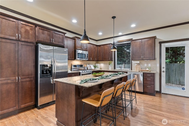 16128 120th Ave NE, Bothell, WA 98011 - kitchen with stainless steel appliances, dark brown cabinetry, light stone counters, a kitchen bar, and ornamental molding
