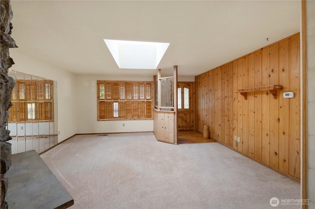 31312 179th Pl SE, Auburn, WA 98092 - unfurnished living room featuring wooden walls, healthy amount of natural light, a skylight, and carpet flooring