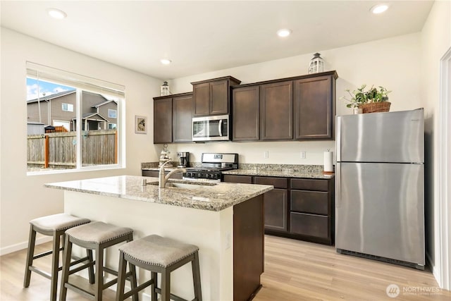 28515 76th Dr NW, Stanwood, WA 98292 - kitchen featuring appliances with stainless steel finishes, dark brown cabinets, light wood finished floors, light stone countertops, and recessed lighting
