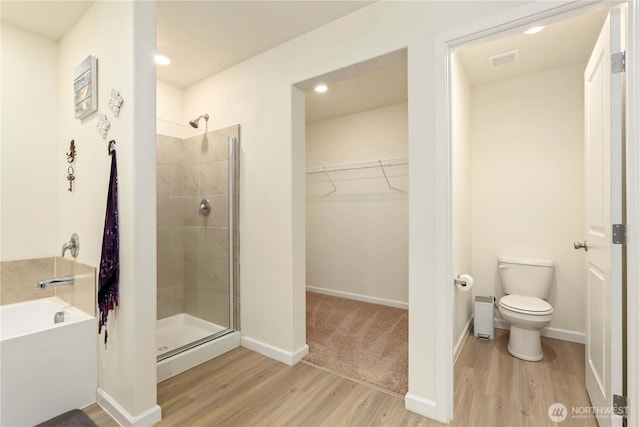 28515 76th Dr NW, Stanwood, WA 98292 - bathroom featuring wood finished floors, a stall shower, a bath, a spacious closet, and recessed lighting