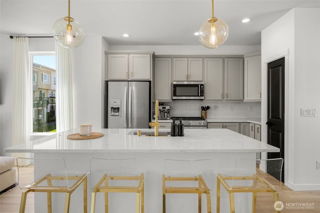 14646 35th Ct NE, Lake Forest Park, WA 98155 - kitchen featuring appliances with stainless steel finishes, gray cabinetry, tasteful backsplash, a kitchen breakfast bar, and decorative light fixtures