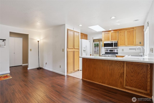 13940 113th Ave NE, Kirkland, WA 98034 - kitchen featuring appliances with stainless steel finishes, a skylight, a peninsula, light countertops, and dark wood-style floors