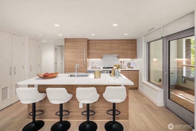 583 Battery St Unit 212N, Seattle, WA 98121 - kitchen featuring modern cabinets, brown cabinetry, light wood-type flooring, light countertops, and a kitchen breakfast bar