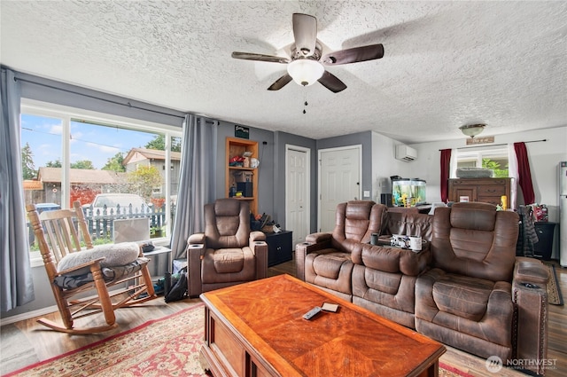 304 Harris St, Kelso, WA 98626 - living area featuring a wall unit AC, healthy amount of natural light, light wood-type flooring, a ceiling fan, and a textured ceiling
