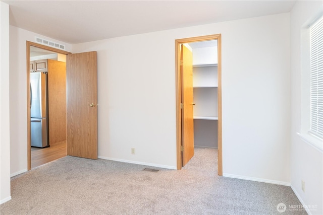 2289 Towne Point Ave, Port Townsend, WA 98368 - unfurnished bedroom featuring freestanding refrigerator, carpet flooring, and a walk in closet