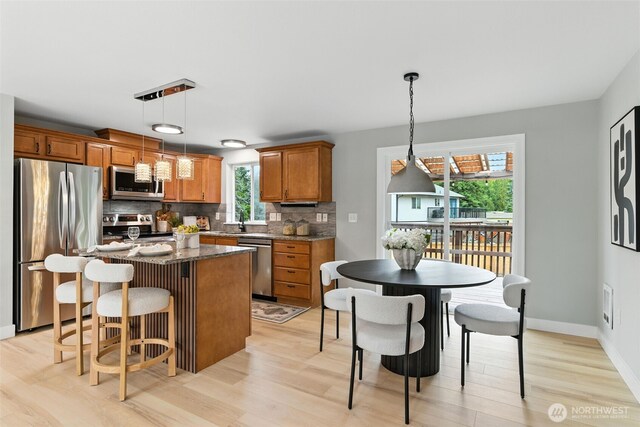 21905 128th St E, Bonney Lake, WA 98391 - kitchen featuring appliances with stainless steel finishes, light wood finished floors, backsplash, a kitchen island, and brown cabinets