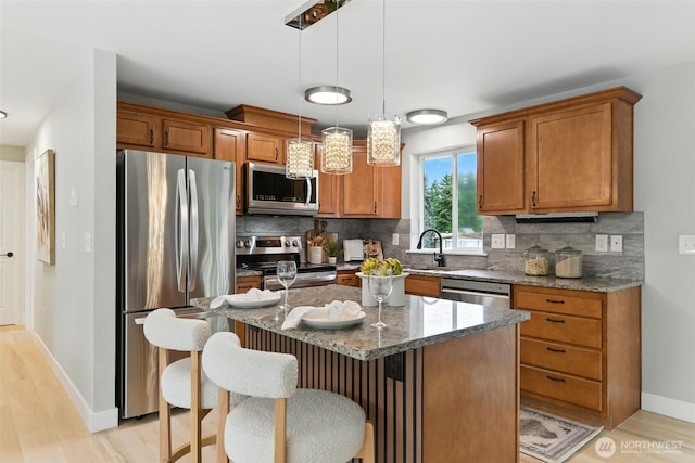 21905 128th St E, Bonney Lake, WA 98391 - kitchen featuring stainless steel appliances, light wood-style floors, brown cabinets, and stone countertops