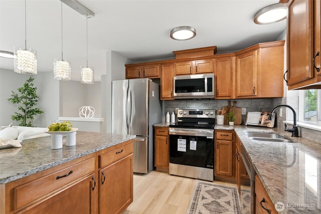 21905 128th St E, Bonney Lake, WA 98391 - kitchen featuring stainless steel appliances, brown cabinets, tasteful backsplash, light wood-style flooring, and light stone countertops