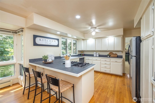 3928 Sorenson Rd, Everson, WA 98247 - kitchen with stainless steel appliances, a peninsula, white cabinets, a kitchen bar, and ceiling fan