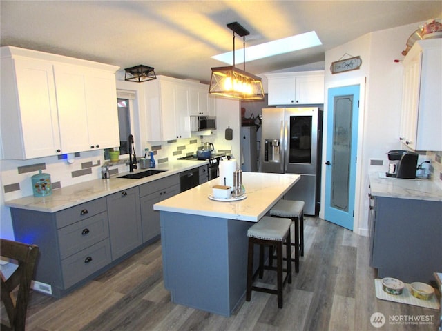 4917 107th Ave SE, Snohomish, WA 98290 - kitchen featuring appliances with stainless steel finishes, a skylight, dark wood-type flooring, a kitchen island, and vaulted ceiling