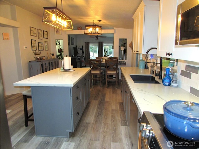 4917 107th Ave SE, Snohomish, WA 98290 - kitchen with wood finished floors, a breakfast bar area, light stone countertops, stove, and decorative light fixtures