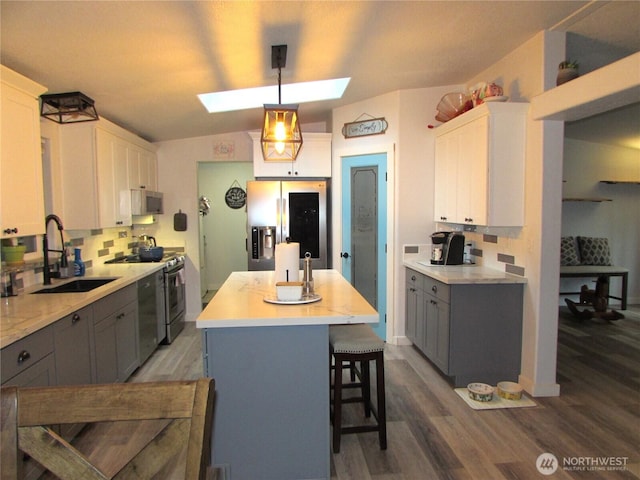 4917 107th Ave SE, Snohomish, WA 98290 - kitchen featuring a skylight, stainless steel appliances, gray cabinets, tasteful backsplash, and wood finished floors