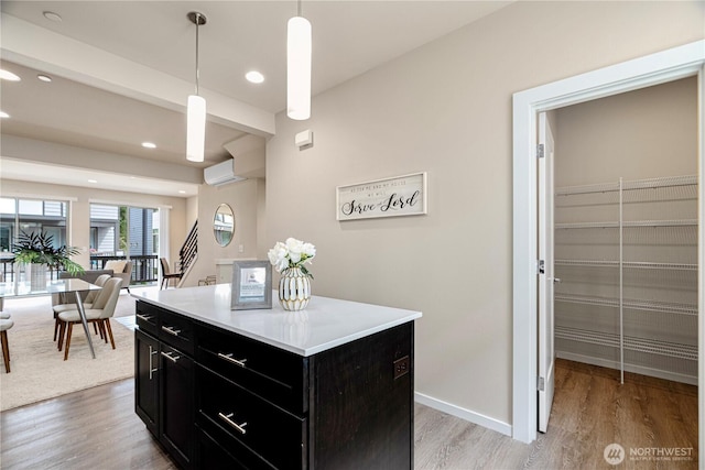 6855 NE 170th St Unit 102, Kenmore, WA 98028 - kitchen with dark cabinetry, light countertops, a center island, light wood-style flooring, and pendant lighting