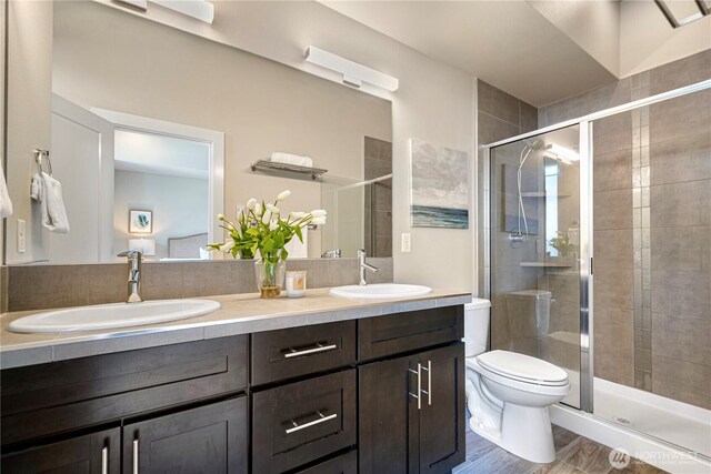 6855 NE 170th St Unit 102, Kenmore, WA 98028 - full bathroom featuring double vanity, a shower stall, and wood finished floors