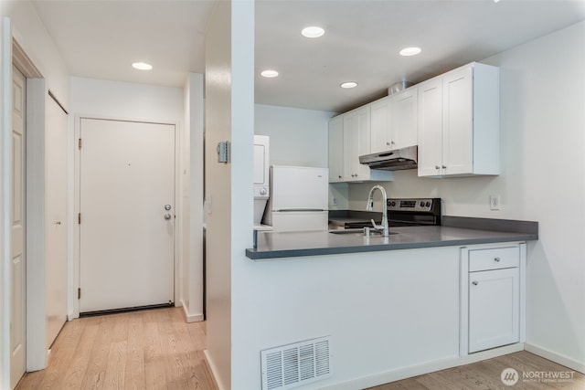 211 E Summit Ave Unit S117, Seattle, WA 98102 - kitchen featuring under cabinet range hood, freestanding refrigerator, dark countertops, light wood finished floors, and white cabinetry