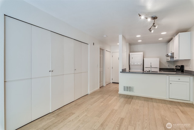 211 E Summit Ave Unit S117, Seattle, WA 98102 - kitchen featuring stacked washer and clothes dryer, dark countertops, white refrigerator, light wood-style floors, and electric range oven