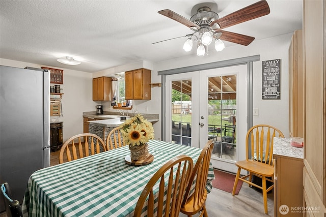 17112 Kinnikinnick Ct SE, Yelm, WA 98597 - dining room with french doors, light wood finished floors, a ceiling fan, and a textured ceiling