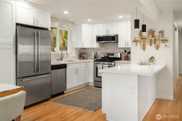 8004 203rd Pl SW, Edmonds, WA 98026 - kitchen with stainless steel appliances, a peninsula, tasteful backsplash, light wood-style flooring, and recessed lighting