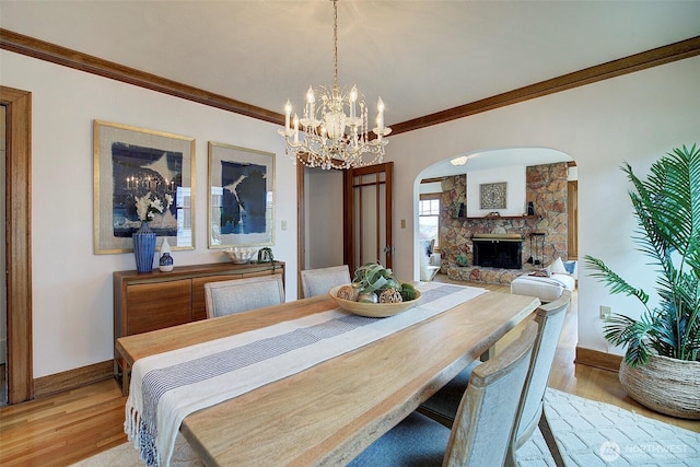 2663 37th Ave SW, Seattle, WA 98126 - dining room featuring arched walkways, a fireplace, ornamental molding, light wood-type flooring, and a chandelier