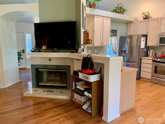 6214 145th St SE, Everett, WA 98208 - kitchen with stainless steel appliances, light wood finished floors, light countertops, a fireplace, and arched walkways