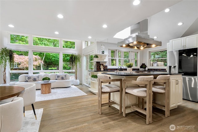 5265 140th Ave NE, Bellevue, WA 98005 - kitchen featuring island exhaust hood, dark countertops, a breakfast bar area, smart refrigerator, and light wood finished floors