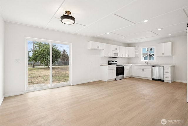910 E 60th St, Tacoma, WA 98404 - kitchen with appliances with stainless steel finishes, plenty of natural light, white cabinetry, recessed lighting, and light wood-style floors