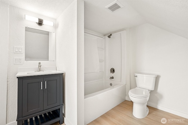 910 E 60th St, Tacoma, WA 98404 - bathroom featuring wood finished floors, vaulted ceiling, vanity, shower / bathtub combination, and a textured ceiling