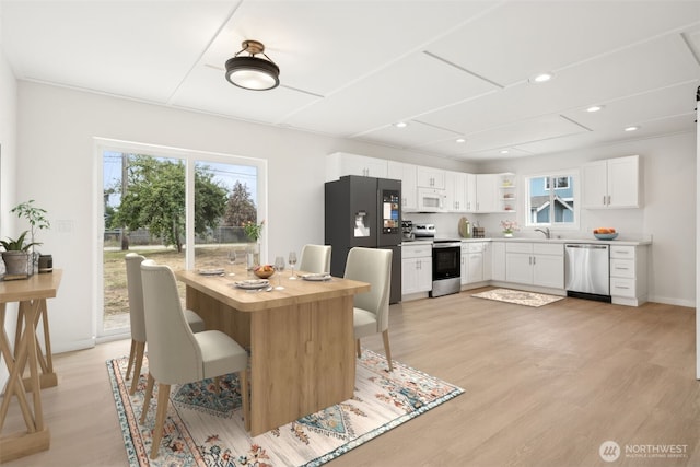 910 E 60th St, Tacoma, WA 98404 - kitchen with stainless steel appliances, healthy amount of natural light, light wood-type flooring, white cabinetry, and recessed lighting