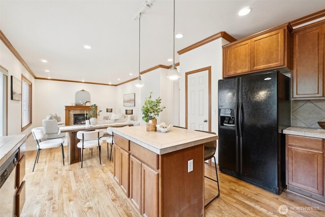 18231 2nd Pl W Unit A, Bothell, WA 98012 - kitchen featuring black fridge with ice dispenser, ornamental molding, light wood finished floors, a center island, and brown cabinets