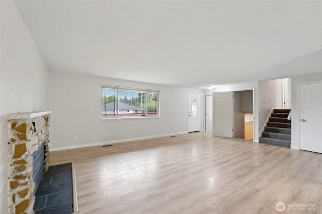 9442 S K St, Tacoma, WA 98444 - unfurnished living room with light wood-style floors, stairs, and a stone fireplace