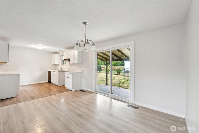 9442 S K St, Tacoma, WA 98444 - kitchen featuring a chandelier, light wood finished floors, white cabinetry, light countertops, and a textured ceiling