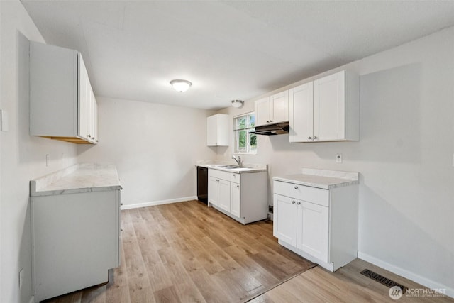 9442 S K St, Tacoma, WA 98444 - kitchen with under cabinet range hood, light wood-style flooring, light countertops, white cabinets, and dishwasher